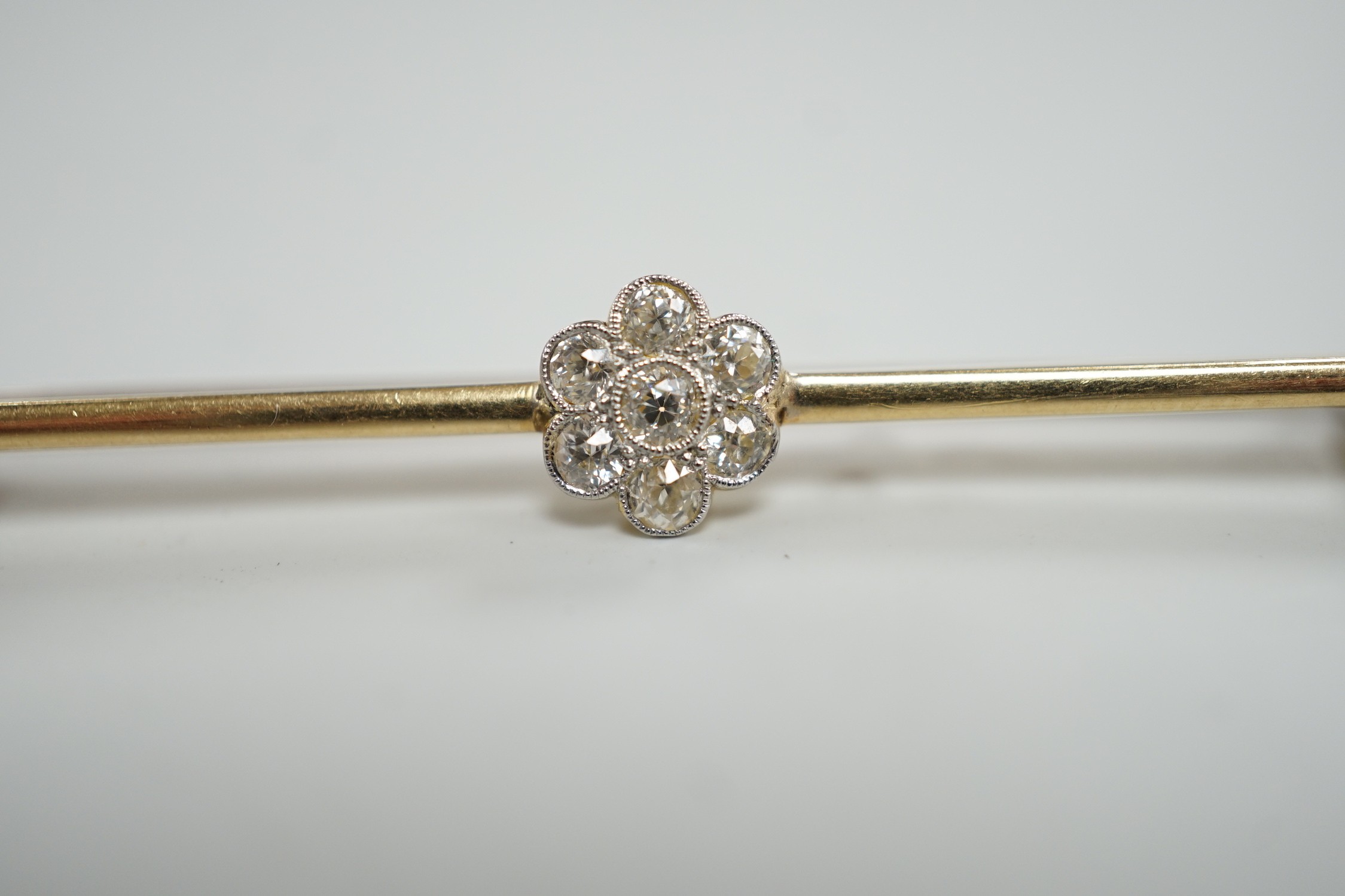 An 18ct and seven stone diamond set flower head cluster bar brooch, 57mm, gross weight 4.7 grams.